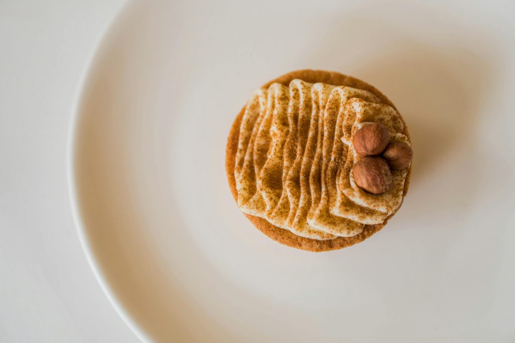 Delicious hazelnut cupcake with creamy frosting on a white plate, ideal for food photography.
