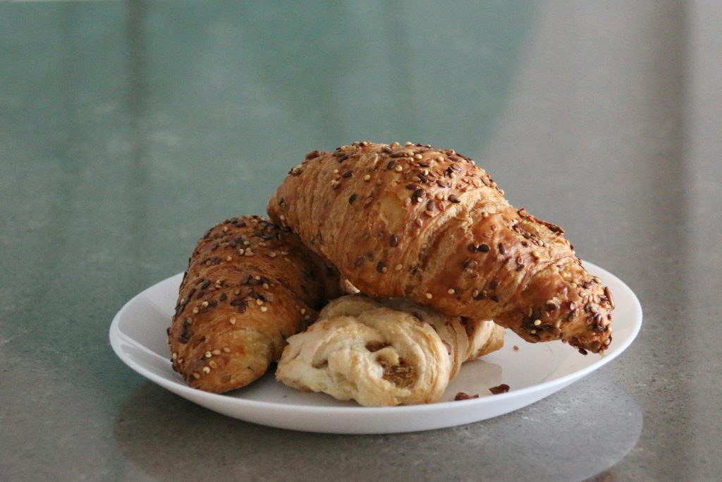 Close-up of freshly baked croissants with sesame seeds on a white plate, perfect for breakfast or snack.