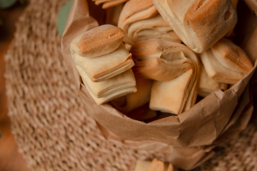 Appetizing rustic pastries in a paper bag placed on a woven mat, providing a cozy, homemade feel.
